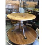 A circular pine kitchen breakfast table raised on a tripod base