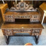 A late 19th century Anglo-Flemish heavily carved oak writing desk with raised top