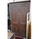 An antique painted pine storage cupboard with panelled doors enclosing fixed shelves