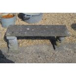 A three piece garden bench with weathered top on squirrel cast pedestals