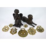 A brown patinated bronze Sphinx, a bronze cherub and seven various horse brasses