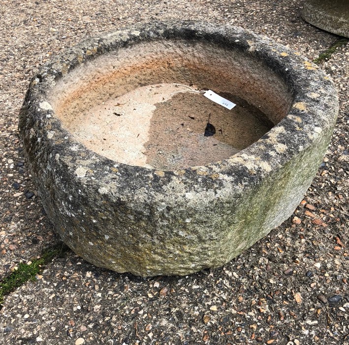 A weathered antique cut and hollowed stone circular trough