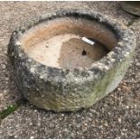 A weathered antique cut and hollowed stone circular trough