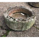 A weathered antique cut and hollowed circular stone trough