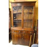 A reproduction mahogany library bookcase with glazed doors over two drawers and panelled cupboards