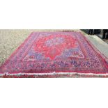 A large Persian Meshad carpet with central navy floral medallion on red ground decorated with floral