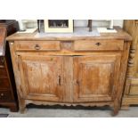 An antique French fruitwood sideboard with two drawers over panelled cupboard doors enclosing a