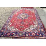 A Persian Tabriz Fichal carpet the large navy floral medallion on red ground with scrolling floral