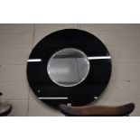 A large circular bevelled edge wall mirror in black glass surround