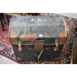 An antique wicker dome-top laundry trunk encased in black, leather bound, canvas cover, with label