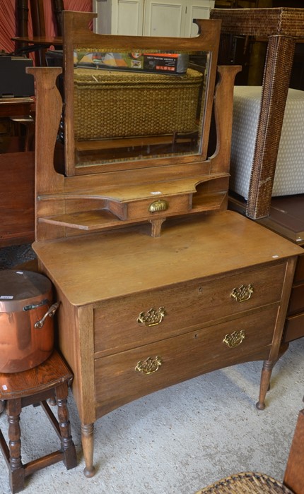 An Arts & Crafts style oak dressing table, the raised back with bevelled mirror and small central