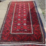 A Persian Balouch rug, the geometric design on dark blue ground within repeating borders 207 x 117