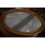 A decorative gilt framed oval mirror with bevelled plate