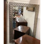 A contemporary wall mirror in woven effect silvered frame