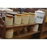 Six stoneware containers and three smaller brown examples, to/w a vintage enamel lidded flour bin (