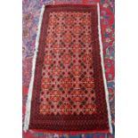 A small Turkoman rug with repeating diamonds on red ground within narrow borders 115 x 54 cm