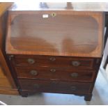 A small Edwardian mahogany fall front bureau with fitted interior and three long drawers raised on