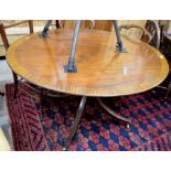 An mahogany cross banded breakfast table, the oval tilt top raised on a turned column and four