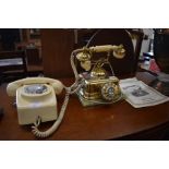 A cream vintage dial telephone for wall mounting and a brass 'Telefone Continentale' cradle phone