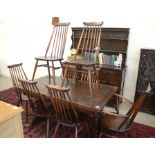 An Ercol dark elm draw-leaf extending dining table on trestle supports united by a pegged