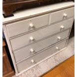 An antique cream painted pine chest of two short and three long drawers with turned pulls -