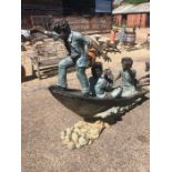 A substantial bronze and copper sculpture of three boys in a boat with a caught fish as a water