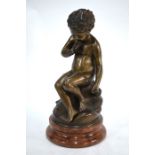 A bronze figure of a contemplative young cherub