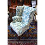 A 19th century mahogany framed wingback armchair, green and beige floral and foliate upholstery with