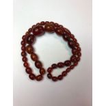 A graduated row of dark oval amber beads
