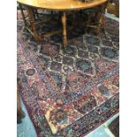 A large old Persian Kirman carpet, the repeating floral lozenge design on camel ground