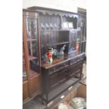 A Jacobean style dark oak dresser, the raised back with open shelves and small side cupboards, on