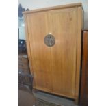 A Chinese light elm brass mounted wardrobe wit two doors enclosing a wooden hanging rail and four