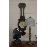 An early 20th century carved oak barometer to/w a tribal carved ebony bust and a brass table lamp (