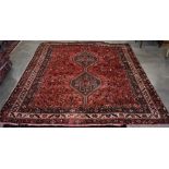 A Persian Shiraz rug, the central double diamond medallion on red ground filled with stylised animal