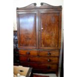 A Regency mahogany linen press, the broken swan-neck pediment with applied roundels, the panelled