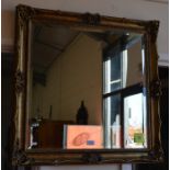 A bevelled rectangular wall mirror in a decorative carved and moulded gilt frame