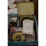 A box containing a vintage horse roulette game, matchbox cover collection, chess pieces, cigarette
