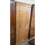 A waxed pine hall cupboard with single full-length panelled door (locked)