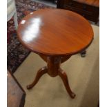 A circular hardwood occasional table on shaped triform supports