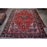 A Persian Hamadan small carpet, stylised floral design  on red ground within guarded navy palmette