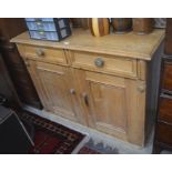 An antique waxed pine cabinet with two drawers over panelled cupboard doors enclosing a single