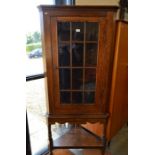 A 19th century corner cabinet on stand with a single glazed door enclosing three shelves, the