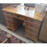 A modern pine twin pedestal desk with nine drawers, brass loop handles, raised on bracket feet