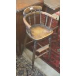 An early 20th century oak spindle back children's high chair with turned supports and stretchers