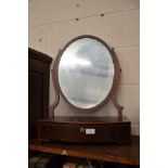 An oval mahogany toilet mirror on three drawer base