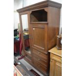 An Edwardian mahogany compactum wardrobe with mirrored door enclosing an open hanging space next