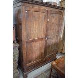 A 19th century mahogany wardrobe with a pair of panelled doors enclosing a hanging rail, raised on