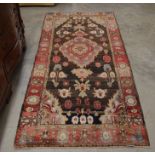 A Persian Hamadan rug, the central floral motif on dark ground, red border decorated with