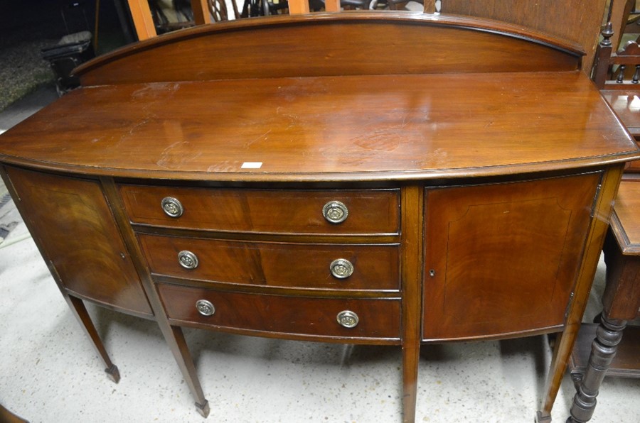 An Edwardian mahogany bowfront sideboard with two cupboards and three central drawers raised on