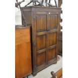 A dark oak linenfold carved hall cupboard, the interior fitted with a brass rail and open